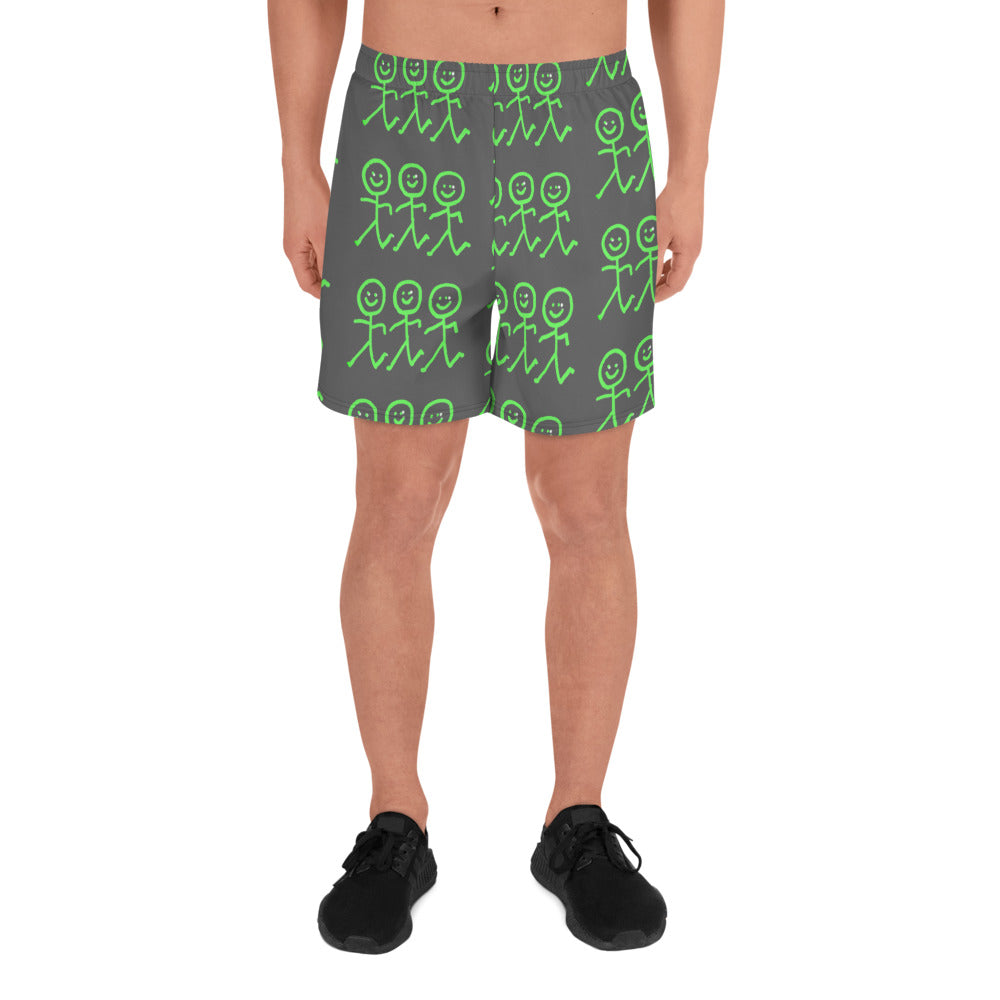 A person standing in Blue Sky Runners' Men's Recycled Athletic Shorts, which are adorned with green stick figures holding hands. The shorts offer a four-way stretch for ease of movement. They are also wearing black sneakers against a light background.