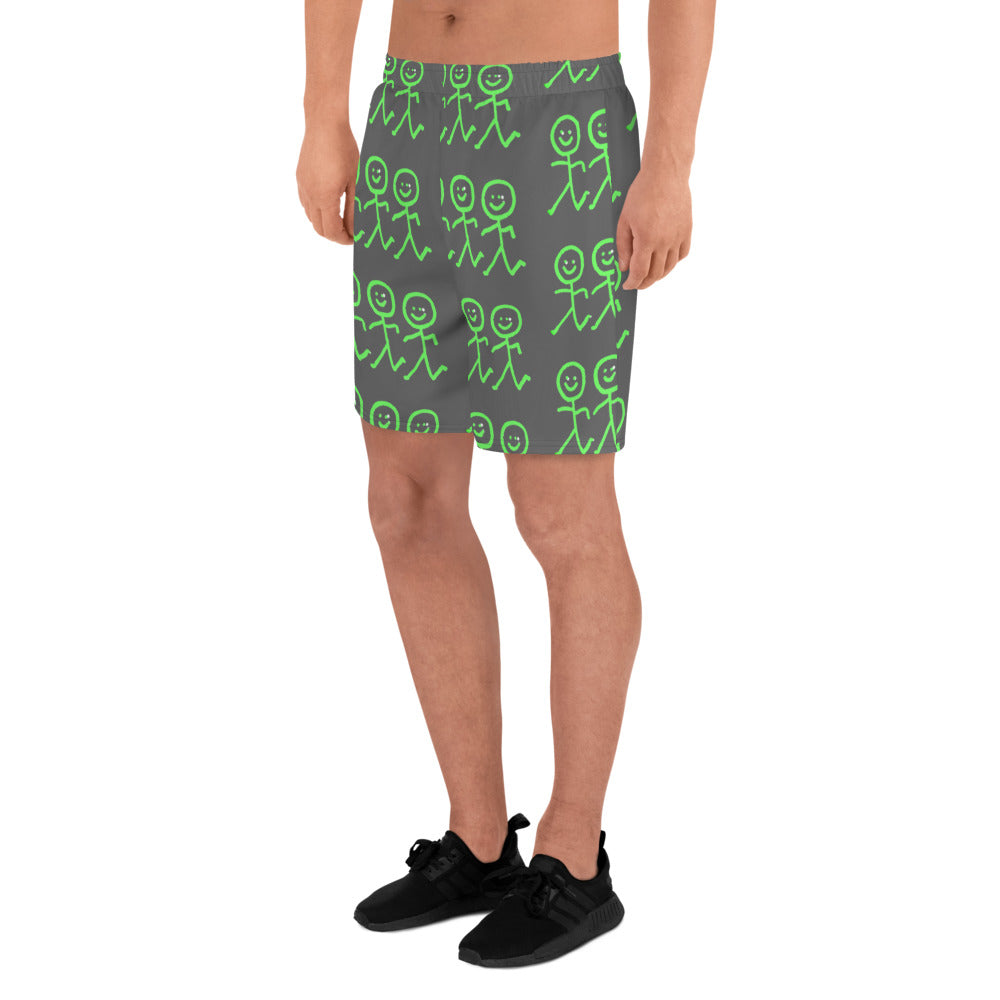 A person is wearing Blue Sky Runners' Men's Recycled Athletic Shorts, featuring a pattern of green stick figures on a dark background. These moisture-wicking long shorts highlight the figure's legs in a side profile, paired with sneakers to complete the athletic look.