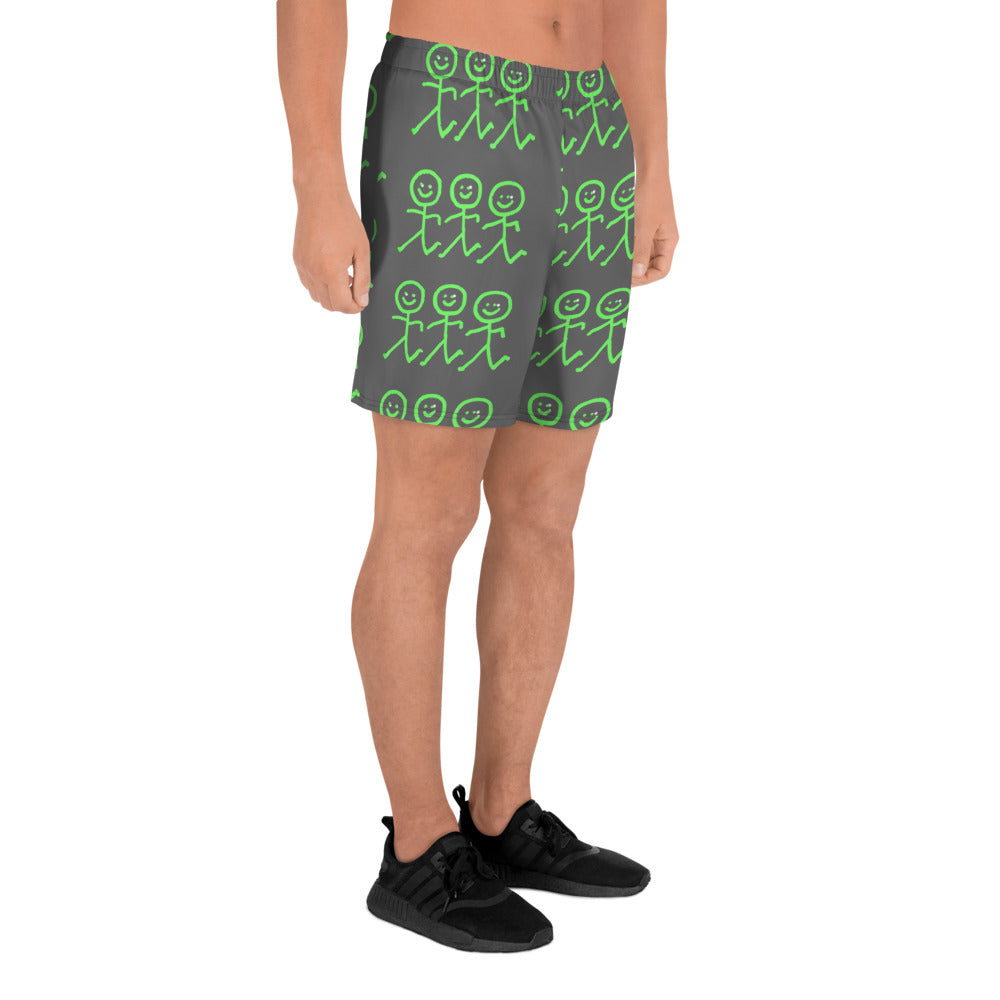 A person wearing Blue Sky Runners' Men's Recycled Athletic Shorts, featuring a playful green stick figure pattern against a long black design, stands with their hands at their sides. The four-way stretch fabric provides comfort, while the vibrant stick figures in various poses add flair to the look, which is completed with black sneakers.