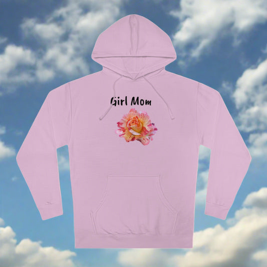 A light pink Printify Girl Mom Hooded Sweatshirt with the phrase "girl mom" in black script above a vibrant floral design, displayed against a blue sky with fluffy clouds.