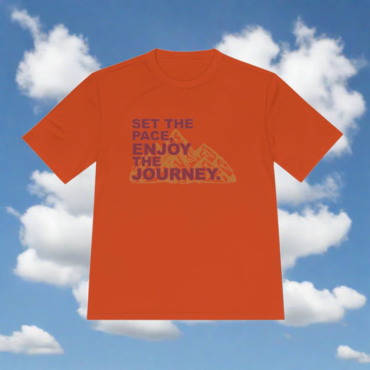 Unisex PaceSetter Moisture Wicking Tee running shirt from Printify with text "set the pace enjoy the journey" and a graphic of mountains, displayed against a blue sky with clouds background.