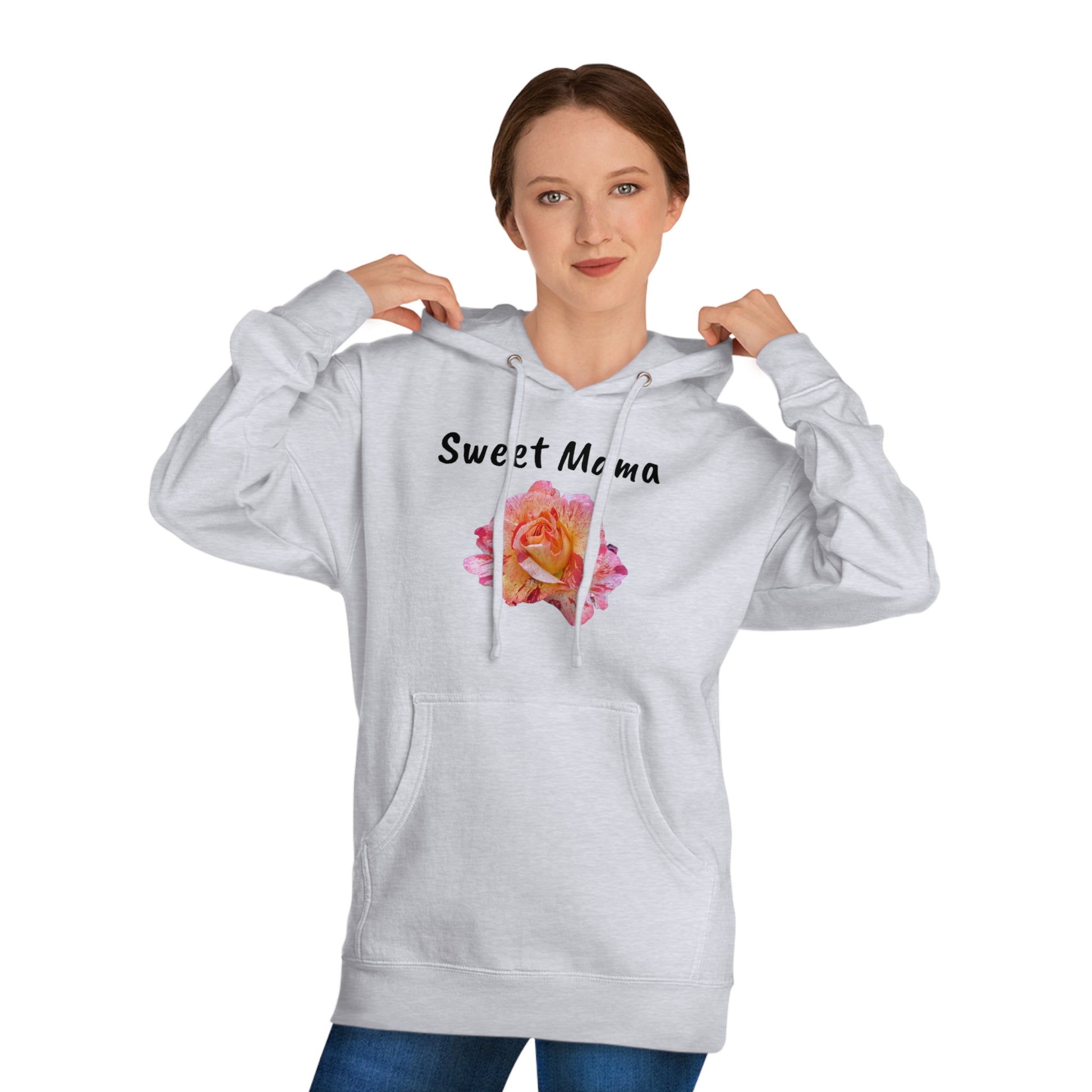 A woman in a light gray Printify Sweet Mama Hooded Sweatshirt with the words "sweet mama" and a pink rose graphic on the front, adjusting the hoodie and looking at the camera.