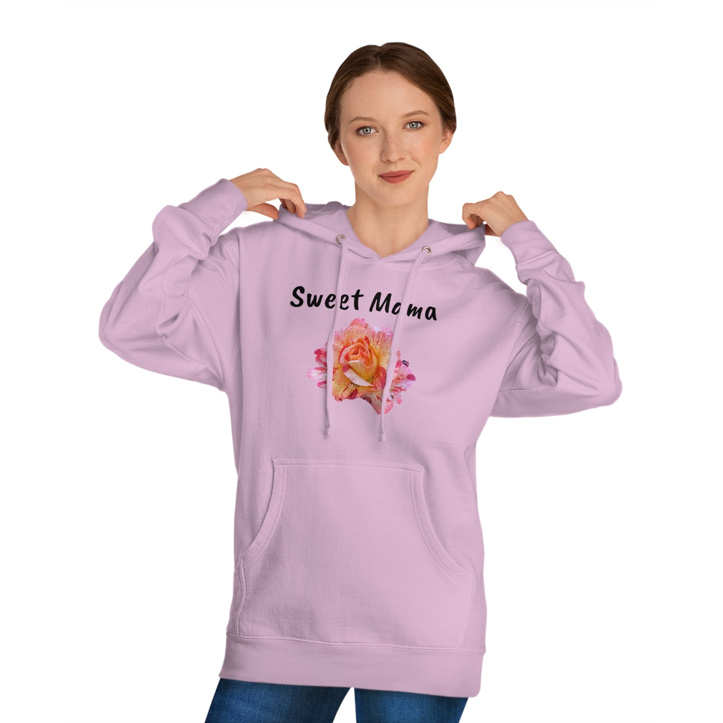 A woman in a light purple Printify Sweet Mama Hooded Sweatshirt with the words "sweet mama" and a floral design on the front, pulling the hood strings, wearing jeans, and looking at