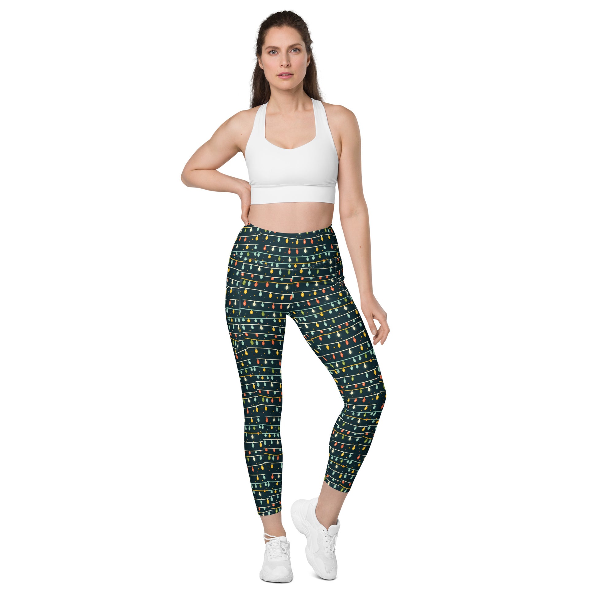 A woman confidently poses wearing a white sports bra and the vibrant Sparkle Stride Splendor leggings with pockets by Blue Sky Runners. Her long hair is pulled back, and she finishes her look with crisp white sneakers against a plain white backdrop.