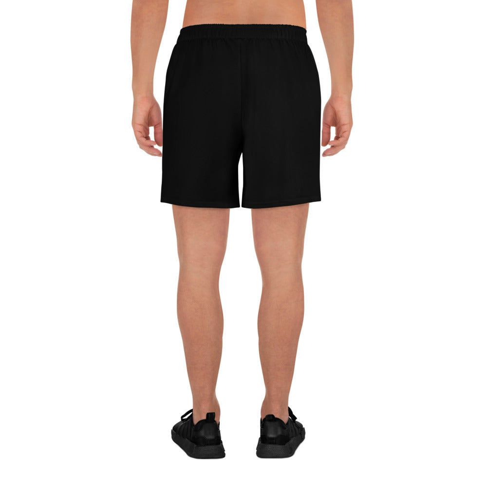 The image shows the back view of a person wearing black Blue Sky Runners Men's Recycled Athletic Shorts made from moisture-wicking fabric and black shoes, standing against a plain white background. The person's legs and lower back are visible.